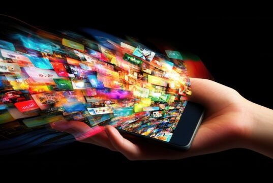 La inversión publicitaria digital en Europa alcanza máximos históricos a costa de sobrecargar a las plantillas Una mano sostiene un teléfono móvil del que emergen numerosas imágenes que representan el crecimiento exponencial de la publicidad digital y la constante exposición de los usuarios a contenidos.