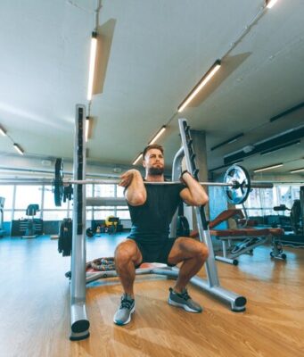 Los beneficios de las cadenas de gimnasios crecen, pero no llegan a sus plantillas Hombre levantando una barra con pesas durante un entrenamiento en un establecimiento que pertenece a una cadena de gimnasios.