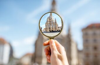 La transparencia local será efectiva si la formación llega a toda la plantilla y en horario laboral Mano sosteniendo una lupa frente a un edificio institucional, como símbolo de la transparencia local en ayuntamientos y diputaciones.