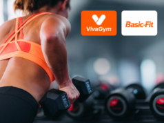 VivaGym y Basic-Fit marcan el ritmo de las fusiones corporativas Mujer entrenando con pesas en un gimnasio junto a los logos de VivaGym y Basic-Fit, dos de las cadenas que protagonizan las fusiones en el sector de instalaciones deportivas y gimnasios en España.
