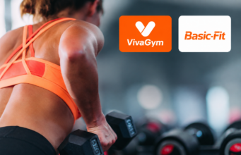 Mujer entrenando con pesas en un gimnasio junto a los logos de VivaGym y Basic-Fit, dos de las cadenas que protagonizan las fusiones en el sector de instalaciones deportivas y gimnasios en España.