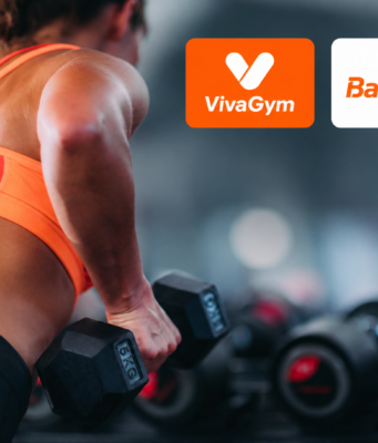 VivaGym y Basic-Fit marcan el ritmo de las fusiones corporativas Mujer entrenando con pesas en un gimnasio junto a los logos de VivaGym y Basic-Fit, dos de las cadenas que protagonizan las fusiones en el sector de instalaciones deportivas y gimnasios en España.