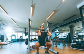 Los beneficios de las cadenas de gimnasios crecen, pero no llegan a sus plantillas Hombre levantando una barra con pesas durante un entrenamiento en un establecimiento que pertenece a una cadena de gimnasios.