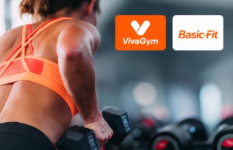 Mujer entrenando con pesas en un gimnasio junto a los logos de VivaGym y Basic-Fit, dos de las cadenas que protagonizan las fusiones en el sector de instalaciones deportivas y gimnasios en España.