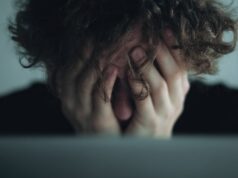 Estrés postvacacional: cuándo la vuelta al trabajo afecta a tu salud Persona abrumada oculta el rostro entre las manos en una imagen que refleja estrés y agotamiento emocional.