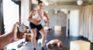 Entrenador cronometra el ejercicio de una mujer en un gimnasio, símbolo de unas plantillas que reclaman mejores condiciones laborales.