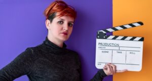 Las cineastas ganan presencia, pero dirigen con la mitad de presupuesto Mujer cineasta sostiene una claqueta, imagen sobre la desigualdad de presupuesto entre directoras y directores en el cine español.
