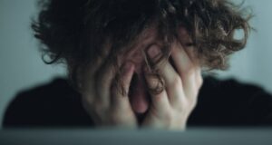 Persona abrumada oculta el rostro entre las manos en una imagen que refleja estrés y agotamiento emocional.
