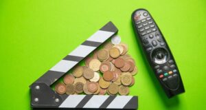 Claqueta de cine junto a monedas y un mando a distancia, en referencia a los recortes y la financiación del sector audiovisual.