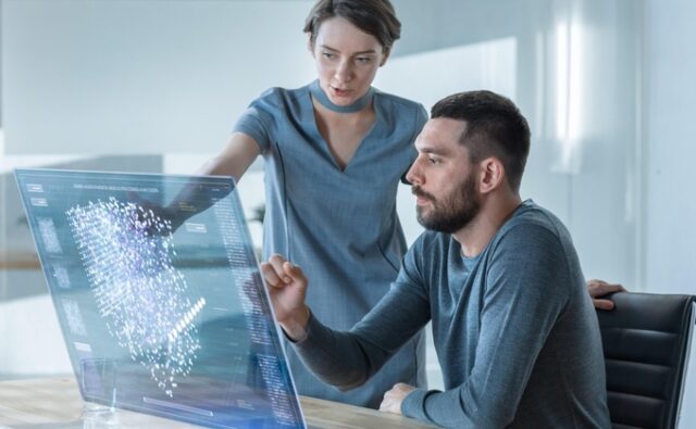 Una empleada le explica a un empleado cómo utilizar la inteligencia artificial en su trabajo.