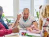 Tres personas conversan y comparten ideas alrededor de una mesa.