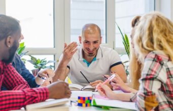 Entendiendo el convenio III: la parte social y el valor de tu voto Tres personas conversan y comparten ideas alrededor de una mesa.