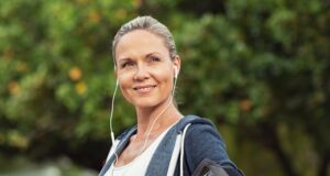 Trabajar en el deporte después de los 45: una carrera sin red Mujer adulta con ropa deportiva y auriculares durante un entrenamiento al aire libre, en una noticia sobre la continuidad laboral en gimnasios después de los 45 años.