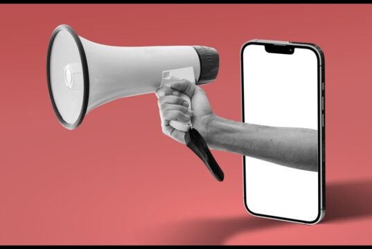 Publicis crece con la IA mientras aumenta la concentración publicitaria : Megáfono que emerge de un teléfono móvil, símbolo de la publicidad digital y de la concentración del sector en grandes grupos.