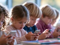 Niños consultan sus teléfonos móviles en una mesa escolar, una escena relacionada con la propuesta europea para proteger a los menores en Internet.