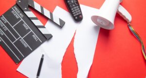 Netflix se suma a la oleada de recortes en el sector audiovisual Claqueta, mando de televisión y megáfono sobre documentos rotos, imagen de los recortes de empleo y la reestructuración en el sector audiovisual.
