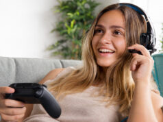 Mujer jugando a videojuegos con cascos y un mando.