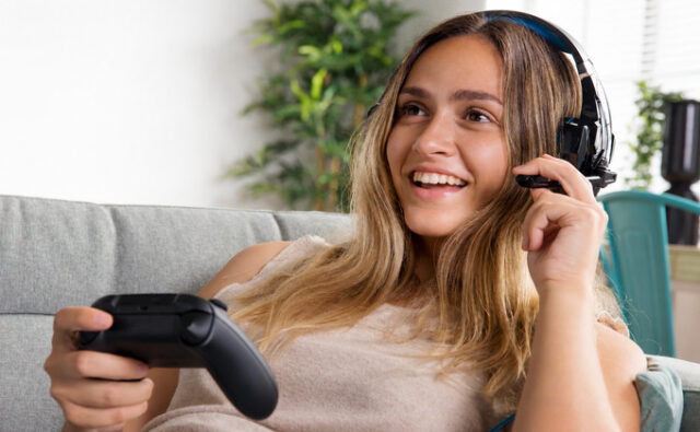 Mujer jugando a videojuegos con cascos y un mando.