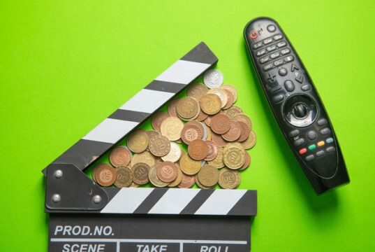 El sector audiovisual alerta del recorte del 30% en AgoraEU Claqueta de cine junto a monedas y un mando a distancia, en referencia a los recortes y la financiación del sector audiovisual.