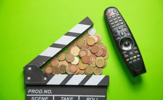 Claqueta de cine junto a monedas y un mando a distancia, en referencia a los recortes y la financiación del sector audiovisual.