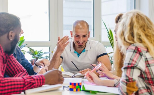 people-sharing-ideas-680x420 Tres personas conversan y comparten ideas alrededor de una mesa.