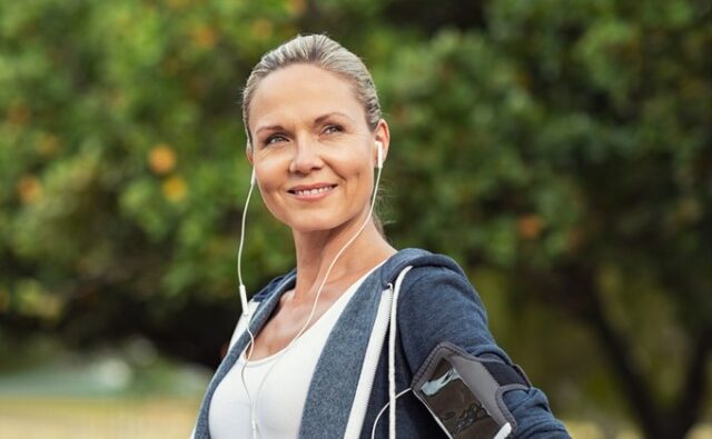 Mujer adulta con ropa deportiva y auriculares durante un entrenamiento al aire libre, en una noticia sobre la continuidad laboral en gimnasios después de los 45 años.